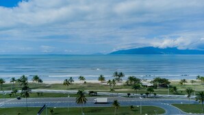 A coastal road with palm trees and a view of the ocean. - Casa Indaiá - Caraguatatuba (Caraguatatuba)