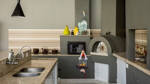 A kitchen with a built-in oven, a sink, and a hanging towel. - Casa Indaiá - Caraguatatuba (Caraguatatuba)