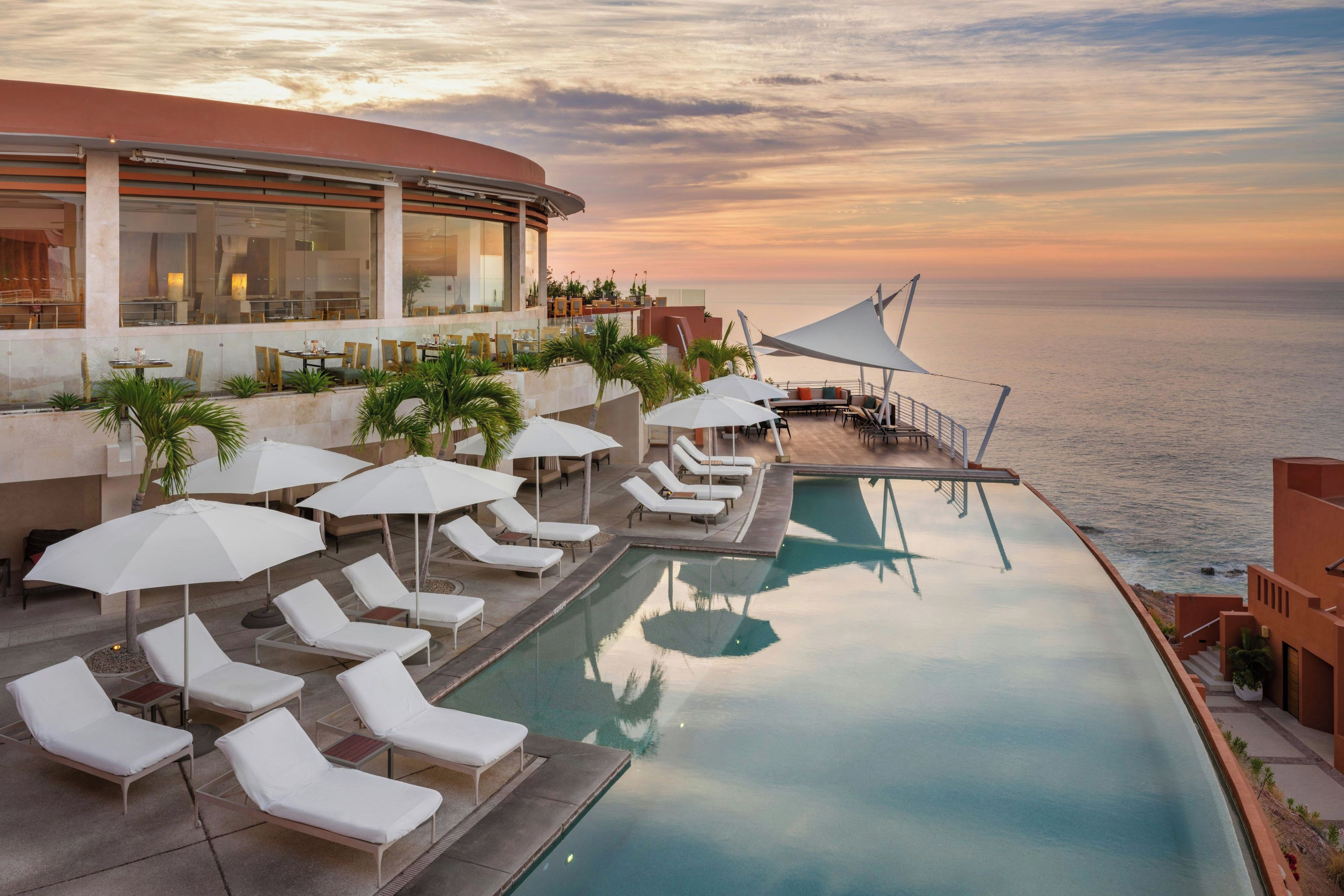 A poolside area with sun loungers and umbrellas, overlooking a body of water.