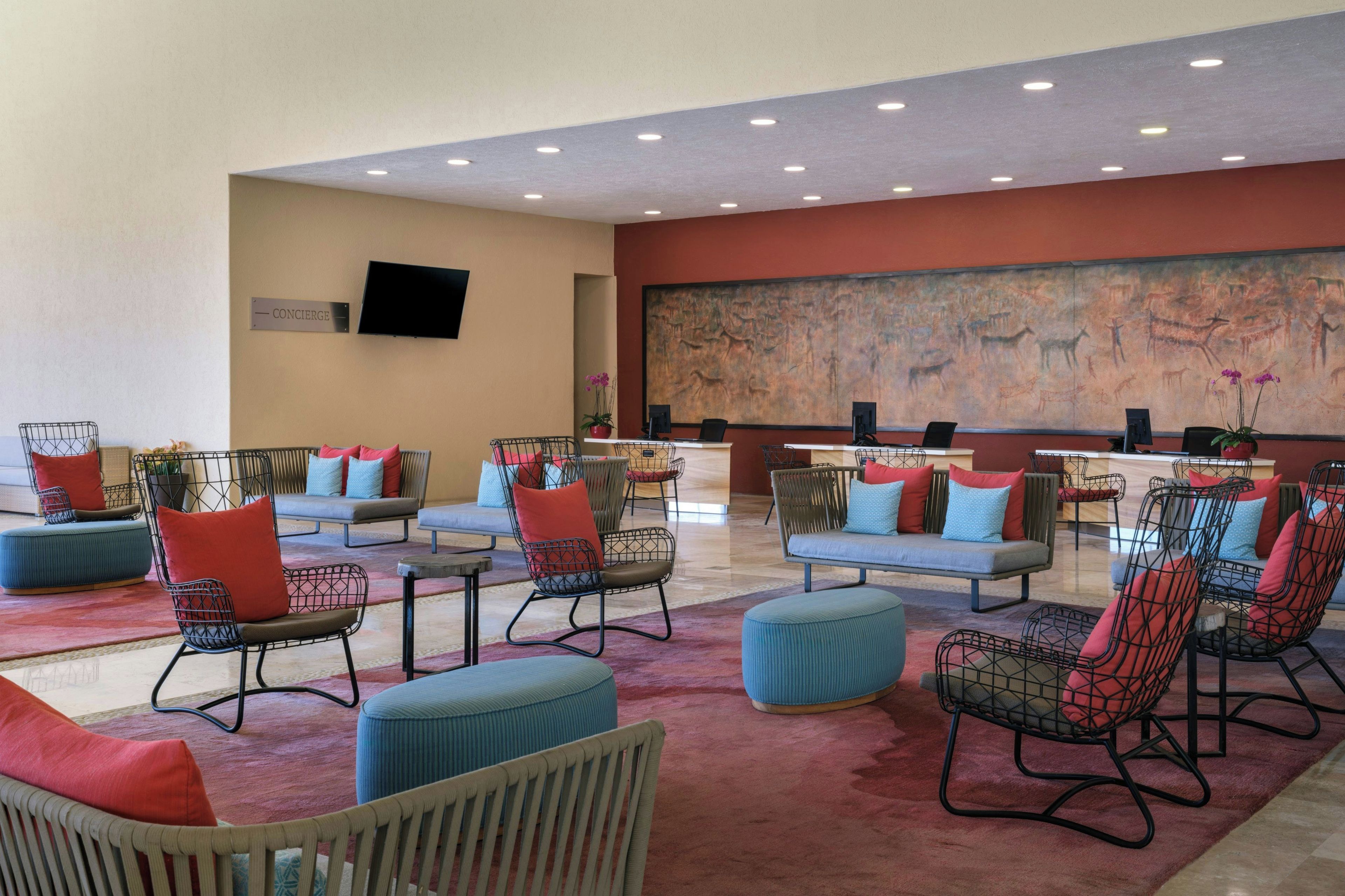 A lobby with seating areas, a reception desk, and a large wall mural.