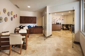 A modern kitchen with wooden cabinets, a dining area with a table and chairs, and a living area with a sofa and decorative wall art. - The Westin Los Cabos Resort Villas - Baja Point (San José del Cabo)