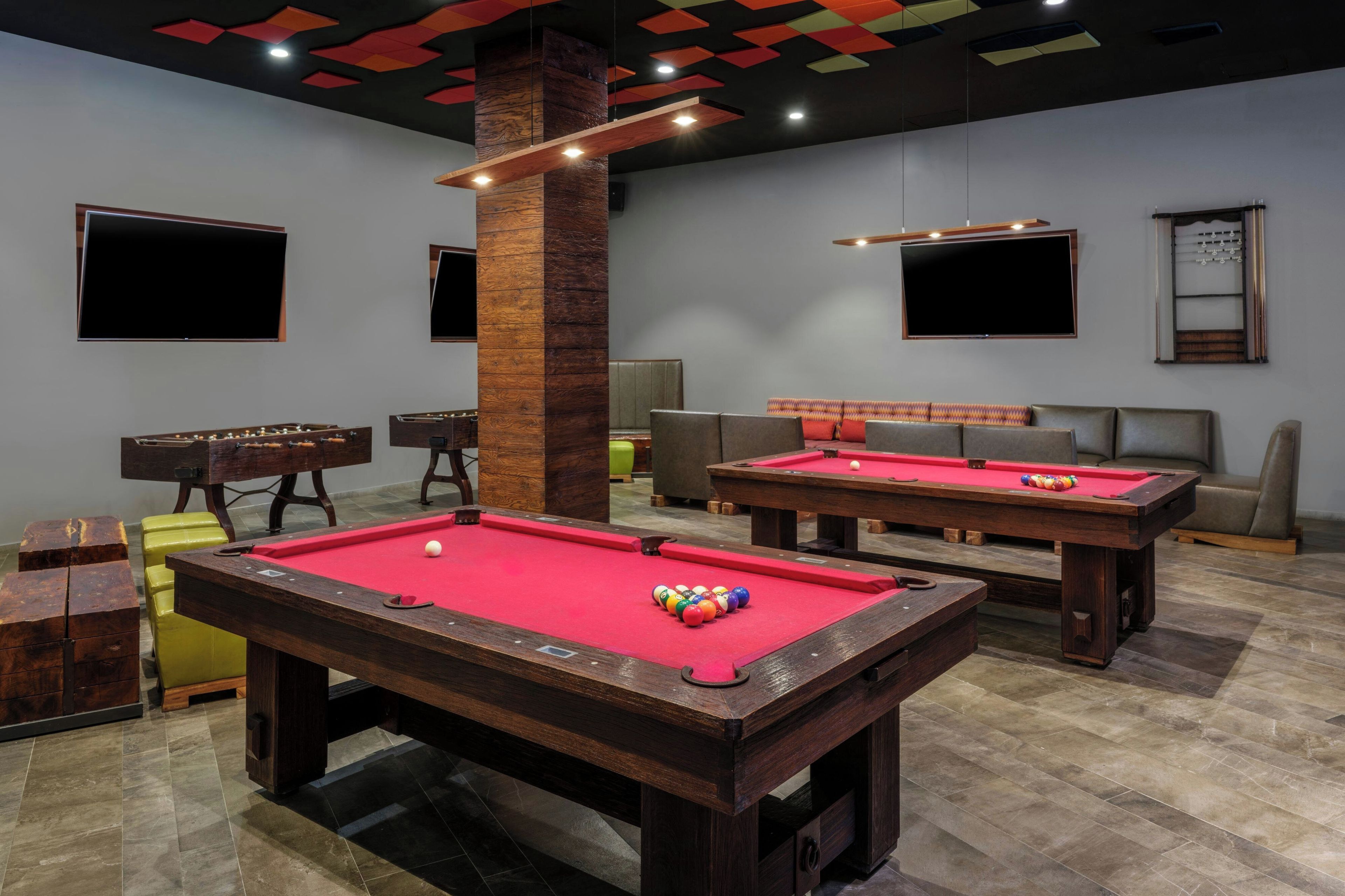 A pool table with a red felt surface, a billiards cue, and a cue ball.