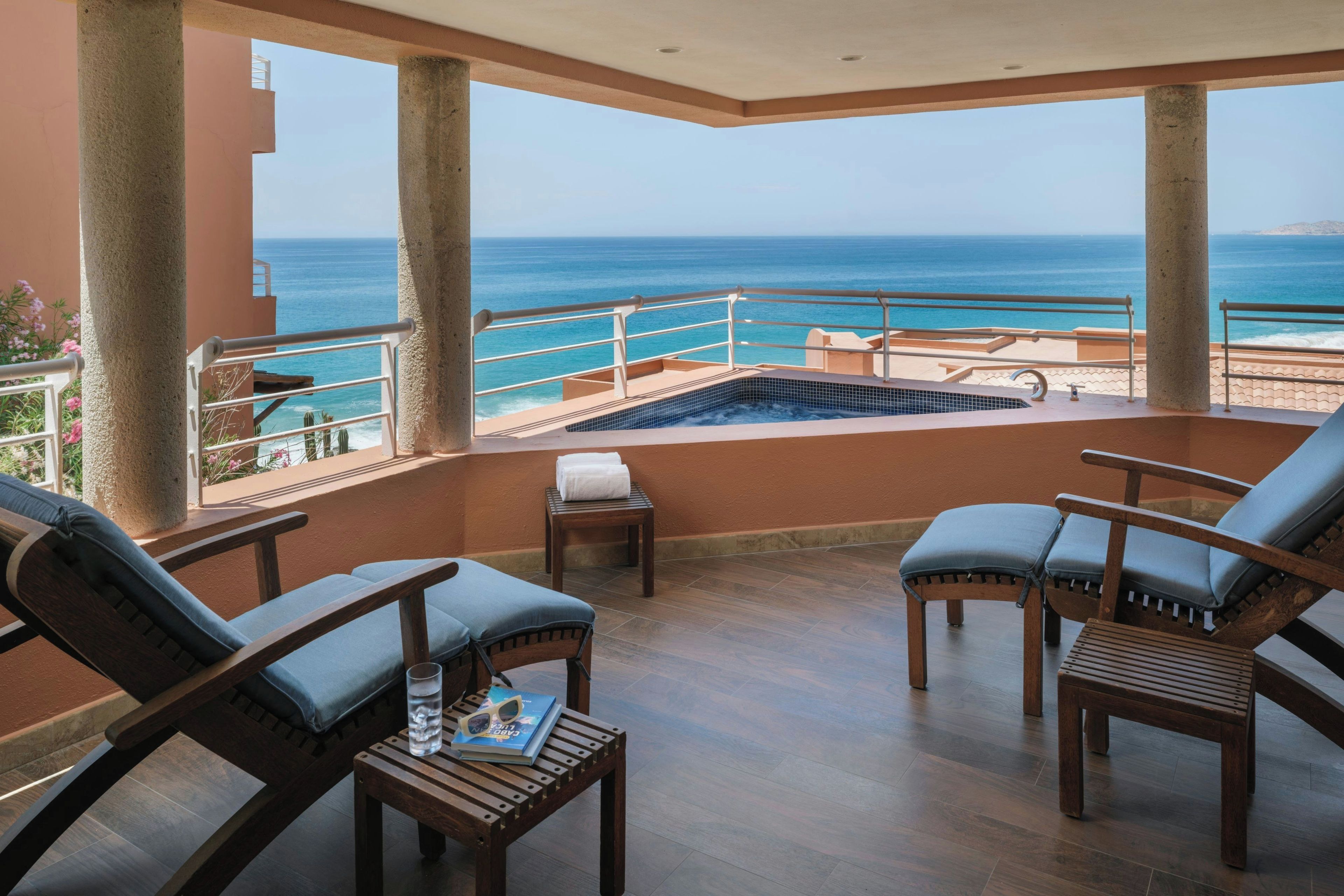 Ein Balkon mit Meerblick, einem Pool und Sitzgelegenheiten.