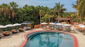 Área de piscina en un resort con sillones, sombrillas y vista despejada de la vegetación tropical circundante.