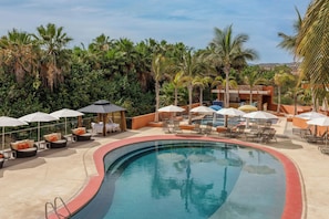 Área de piscina en un resort con sillones, sombrillas y vista despejada de la vegetación tropical circundante.