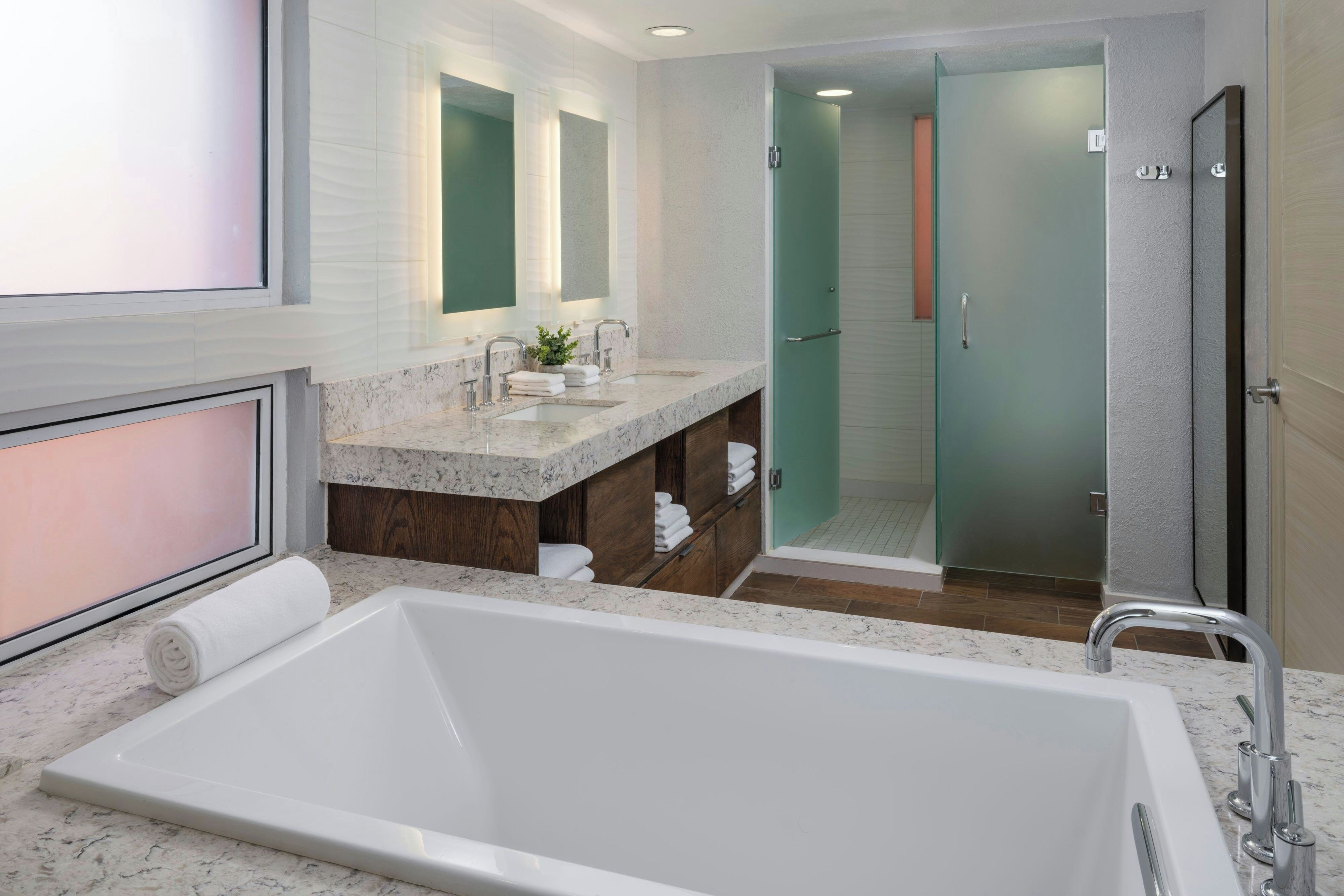 Un baño moderno con una bañera grande, un tocador doble y una cabina de ducha de vidrio.
