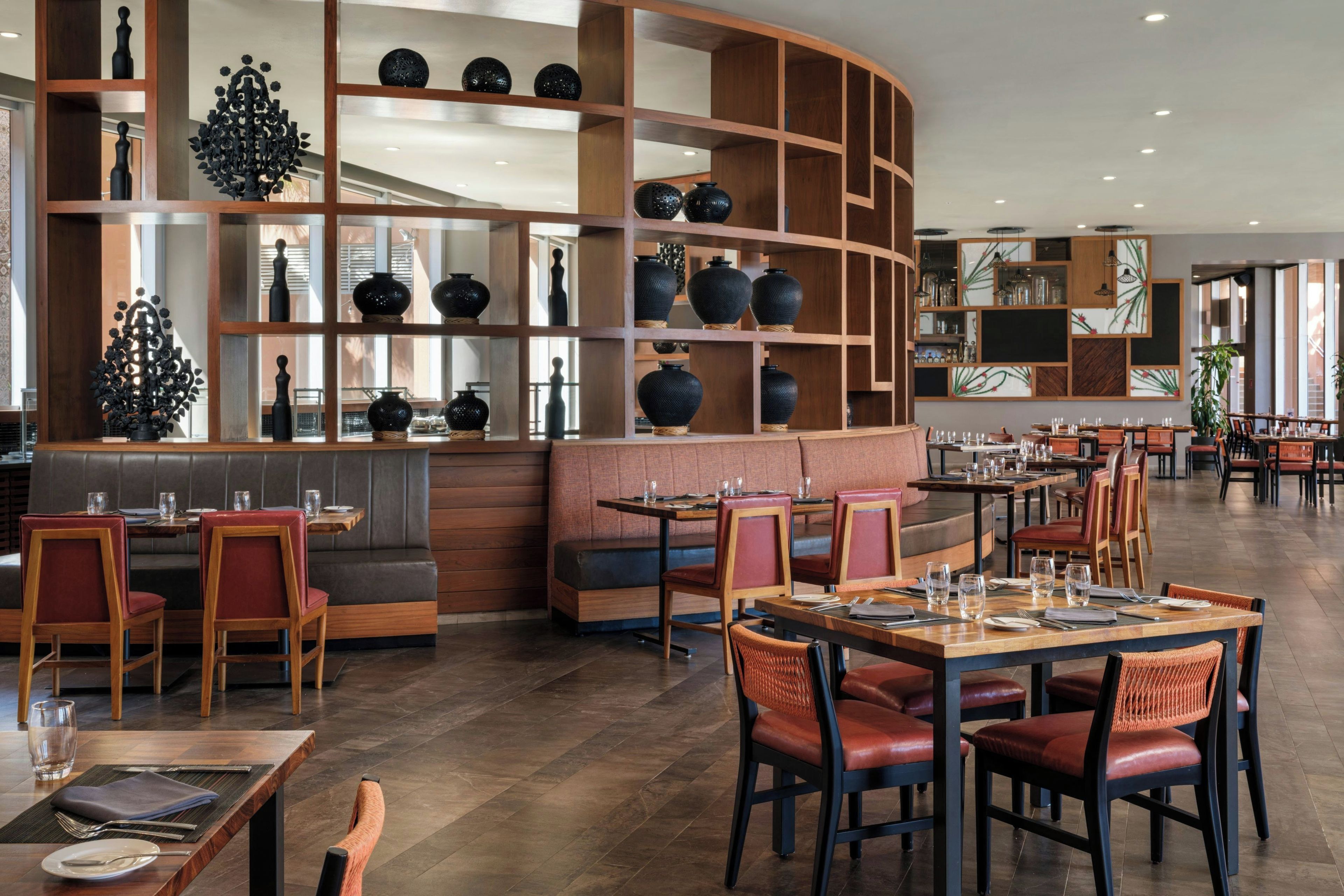Een restaurantinterieur met zitjes, tafels en een decoratieve wand met vazen.