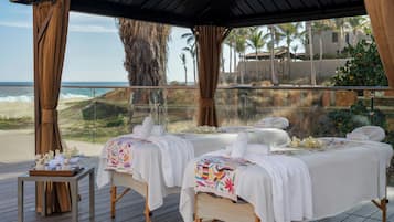 Un spa situé en bord de mer, doté de deux tables de massage, d’une terrasse en bois et offrant une vue sur l’océan.