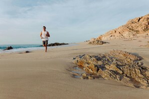 A person running on a sandy beach with rocky outcrops and a clear sky. - The Westin Los Cabos Resort Villas - Baja Point (San José del Cabo)