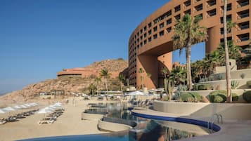 Un resort con piscina, sillones de descanso y palmeras.