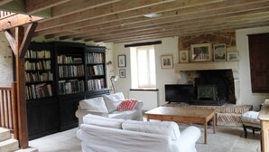 A cozy living room with a fireplace, bookshelves, and a staircase. - Charming country house (Verruyes)
