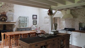 A rustic kitchen with a wooden island, white cabinets, and a brick wall. - Charming country house (Verruyes)