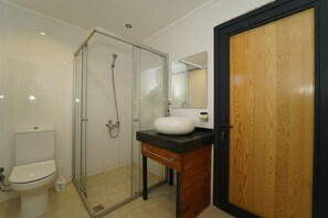 A bathroom with a glass-enclosed shower, a white sink, and a wooden vanity. - Cragus Inn (Fethiye)