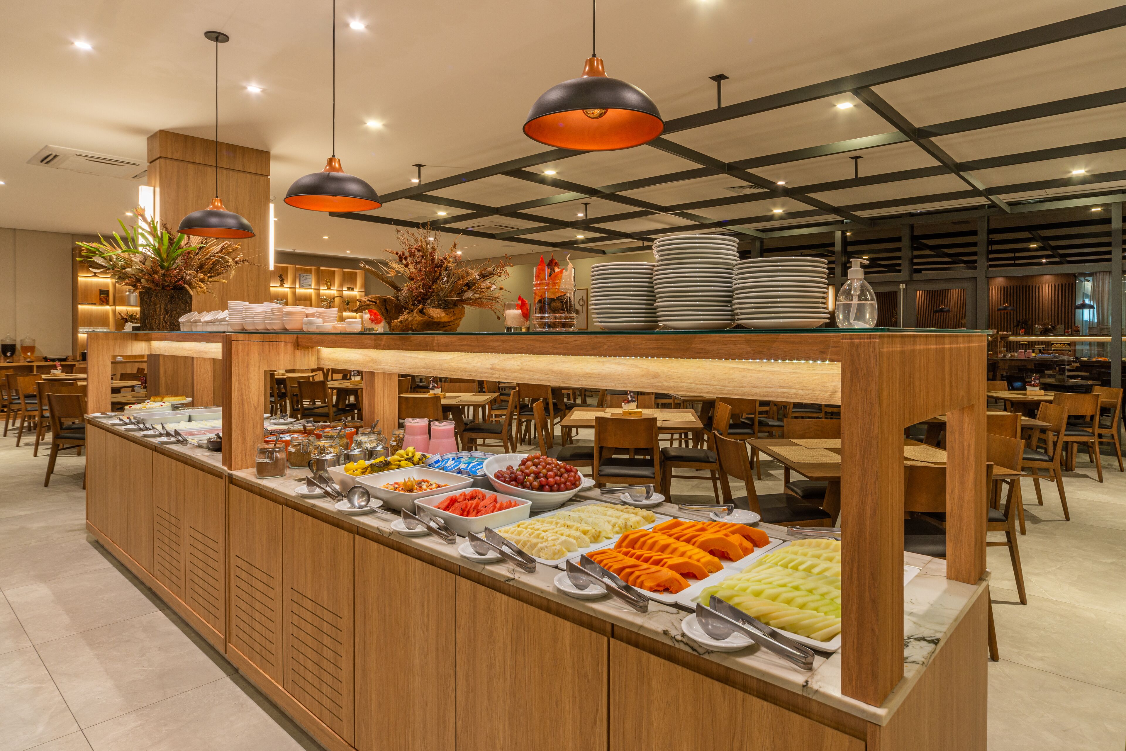 A buffet area with various food options, wooden furniture, and pendant lighting.