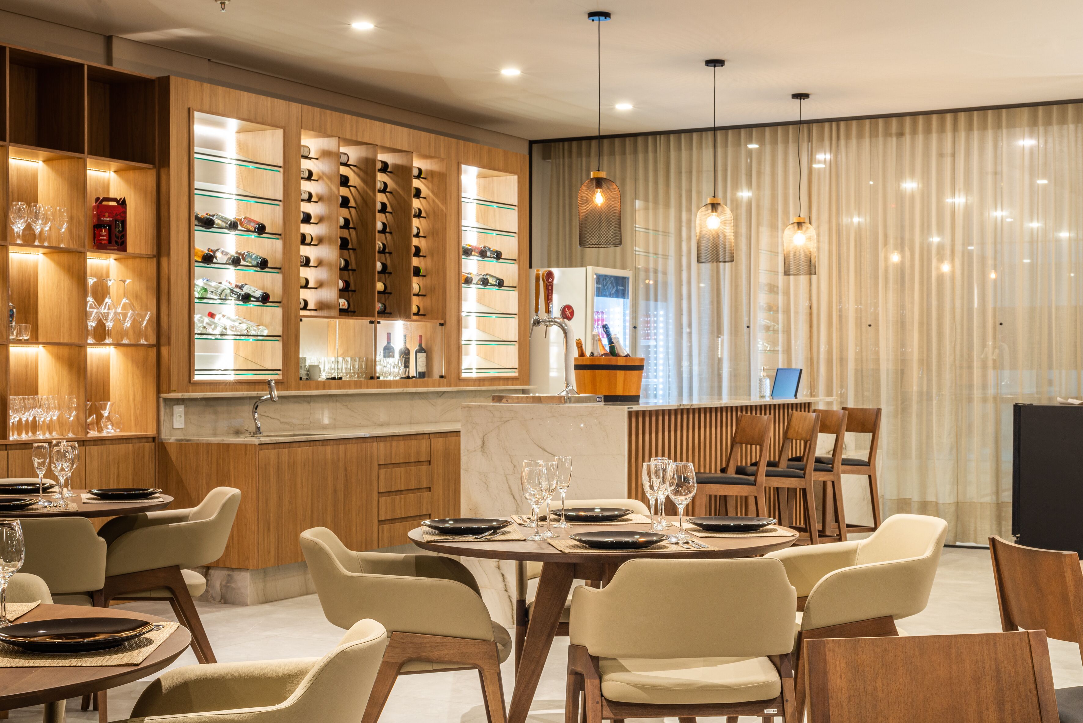 A modern dining area with a bar, wooden shelving with glasses, and a marble countertop.