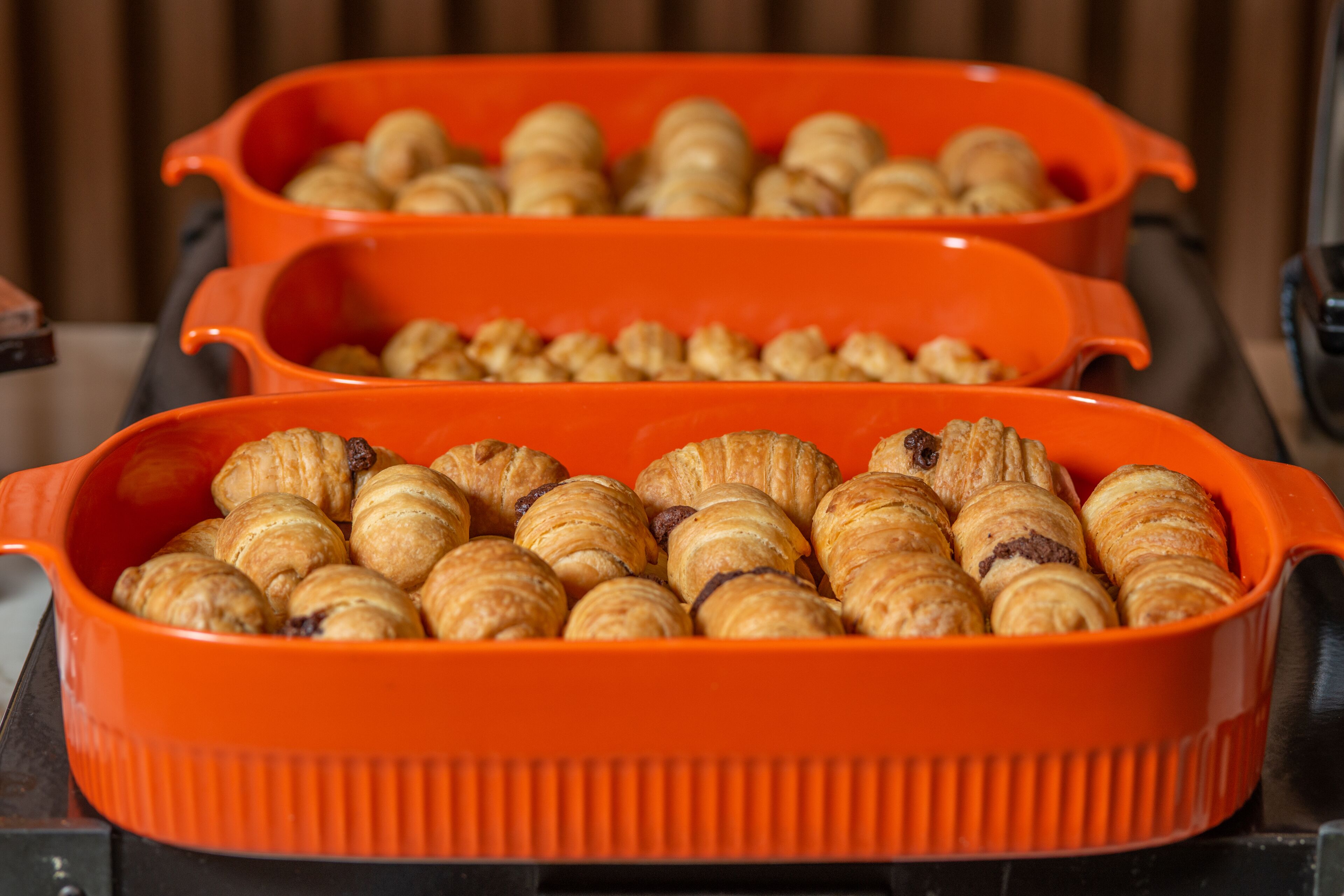 Une pile de croissants dans un plat de cuisson orange.