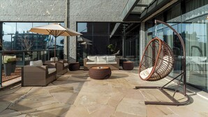 An outdoor seating area with wicker furniture, a hanging chair, and a glass balustrade. - Laghetto Canela (Canela)