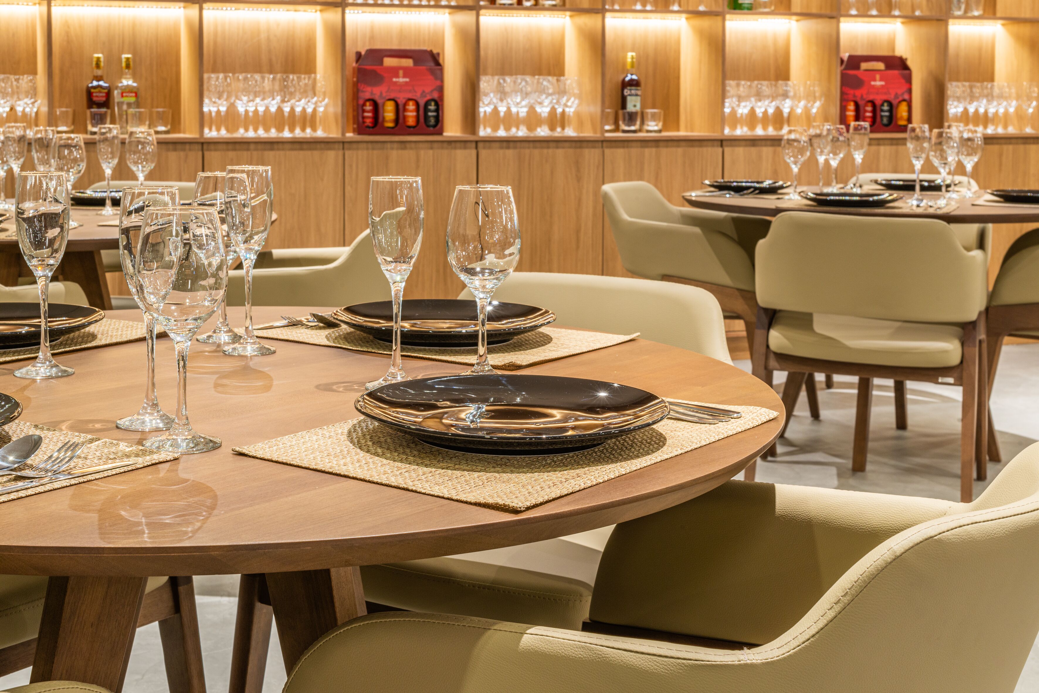 Un restaurante bien iluminado con mesas redondas dispuestas para comer, con cristalería y vajilla transparente.