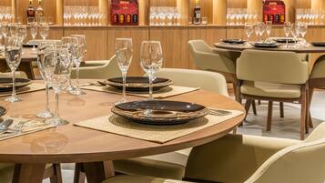 Un restaurante bien iluminado con mesas redondas dispuestas para comer, con cristalería y vajilla transparente.