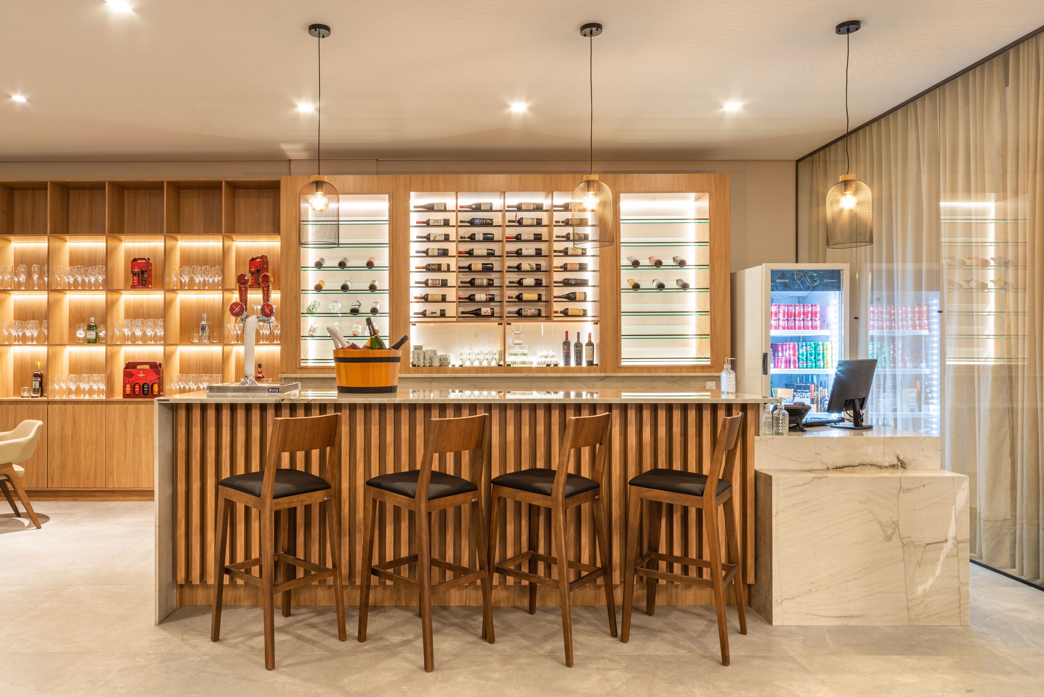 A bar area with wooden chairs, a marble counter, and shelves of bottles and glasses.