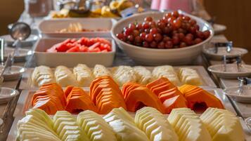 A buffet with various fruits and vegetables, including sliced carrots, apples, and grapes.