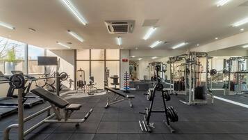Ett gym med olika typer av träningsutrustning, inklusive löpband, styrketräningsmaskiner och fria vikter.