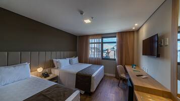 Habitación de hotel con dos camas, un escritorio, una silla, un televisor y una ventana con vistas.