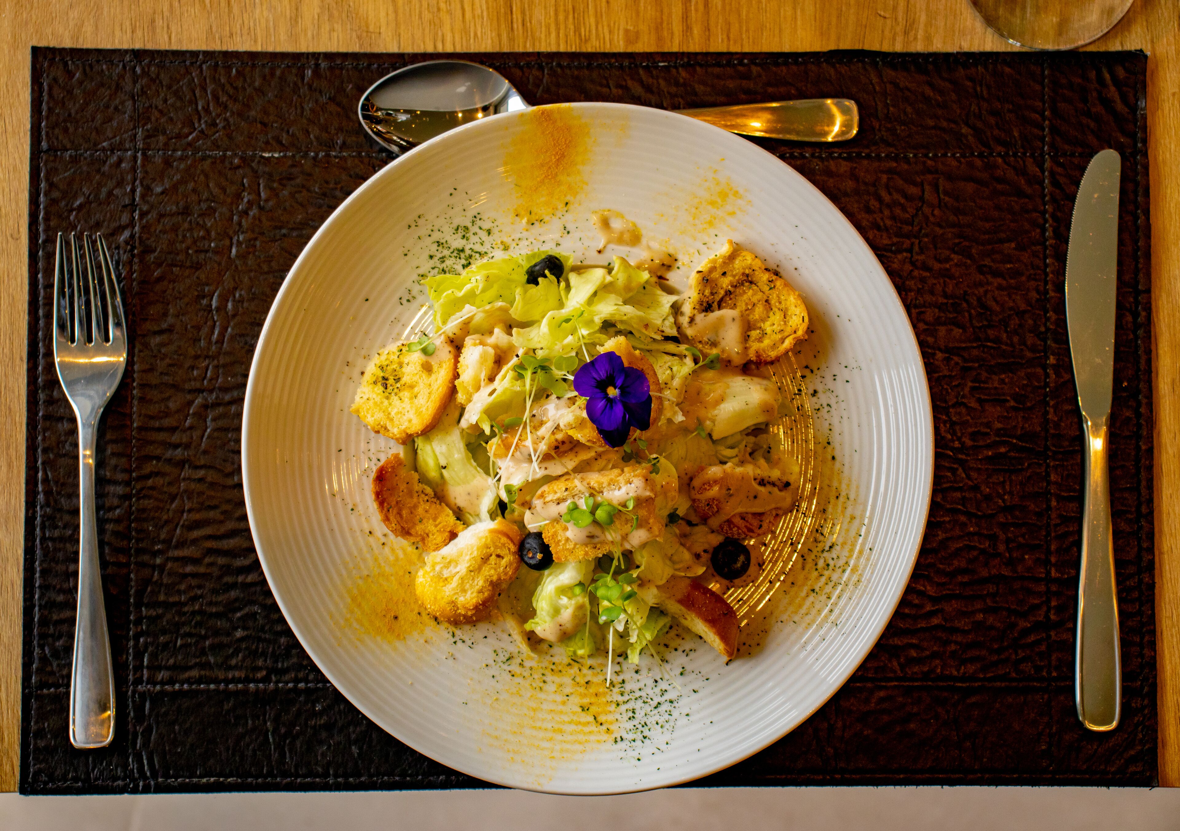 Un plato blanco con comida sobre un mantel individual oscuro.