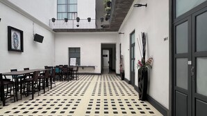 A spacious courtyard with a patterned floor, a balcony with hanging plants, and a framed picture on the wall. - Hotel Alhaja Puebla Centro Histórico (Puebla)