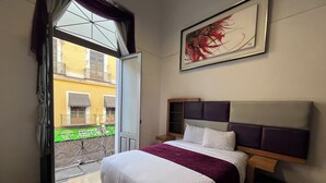 A hotel room with a bed, a window with curtains, a balcony, and a painting on the wall. - Hotel Alhaja Puebla Centro Histórico (Puebla)