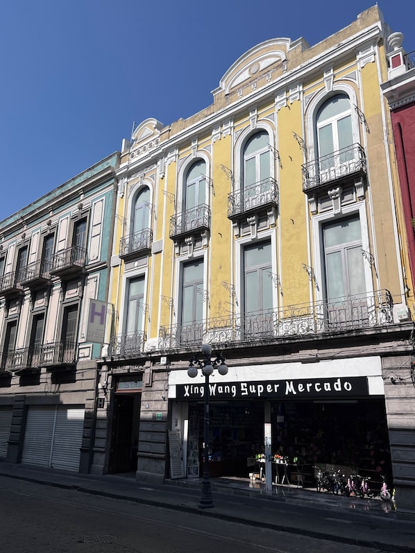 A building with a storefront named "Xing Wang Super Mercado" featuring ornate balconies and a classic architectural style.