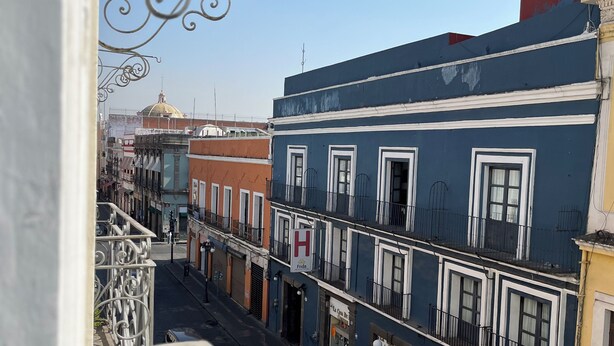A street view with buildings, a clear sky, and a person walking. - Hotel Alhaja Puebla Centro Histórico (Puebla)