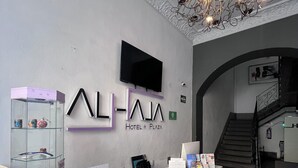 A reception desk with a modern design, a mounted TV, and a chandelier. - Hotel Alhaja Puebla Centro Histórico (Puebla)