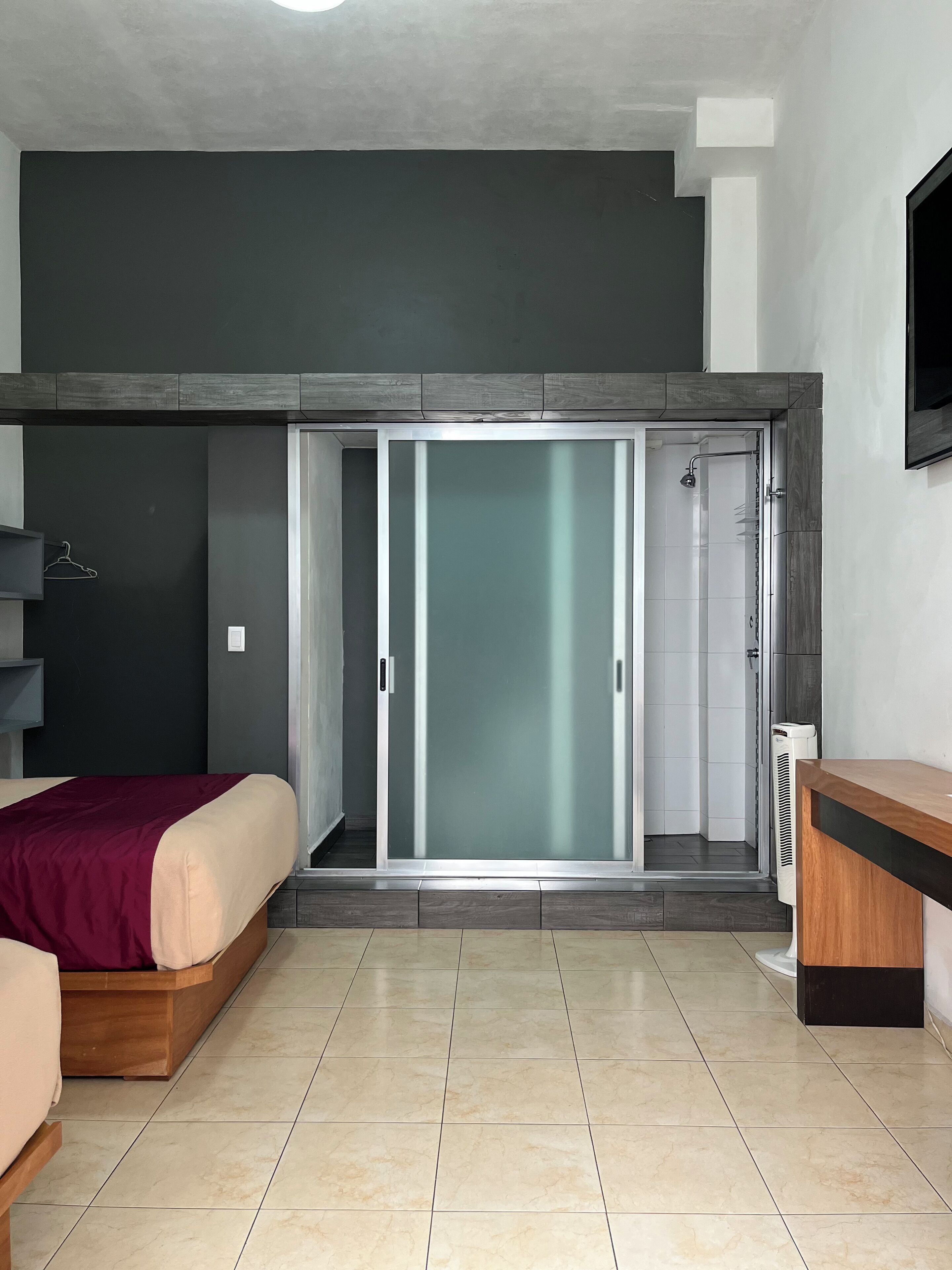 Una camera da letto moderna con un letto, un armadio e un box doccia integrato.