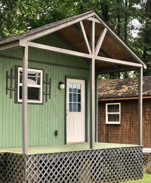 A small, single-story wooden structure with a green exterior, a white door, and a small porch area. - Hales Bar Marina and Resort (Guild)
