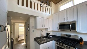 A modern kitchen with white cabinets, a stainless steel stove, a microwave, and a sink. - Hales Bar Marina and Resort (Guild)