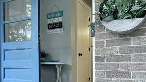 A blue door leading to a room with a small table and a sign reading "Welcome to the Beach."