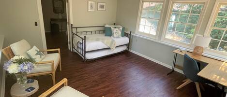 A spacious room with a bed, two chairs, a desk, and a ceiling fan.
