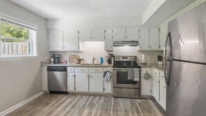 Une cuisine moderne avec des meubles blancs, des appareils en acier inoxydable et un plancher en bois.