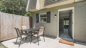 Une terrasse extérieure avec une table et des chaises, une clôture en bois et un mur en briques.