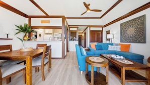 Un vaste espace de vie comprenant une table à manger en bois, un canapé bleu et un ventilateur de plafond.