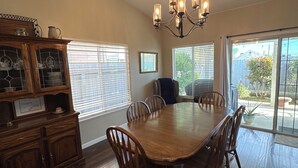 A dining room with a wooden table and chairs, a chandelier, and a cabinet with glass doors.