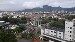 A cityscape with a mix of residential and commercial buildings, a prominent yellow crane, and a mountain in the background. - apartamento amoblado una habitacion (pereira)