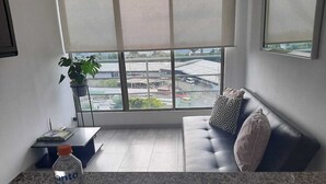 A modern living room with a sofa, a small table with a plant, and a water bottle on a granite countertop. - apartamento amoblado una habitacion (pereira)