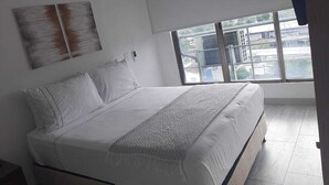 A modern bedroom with a large bed, a window with a view of buildings, and a ceiling fan. - apartamento amoblado una habitacion (pereira)