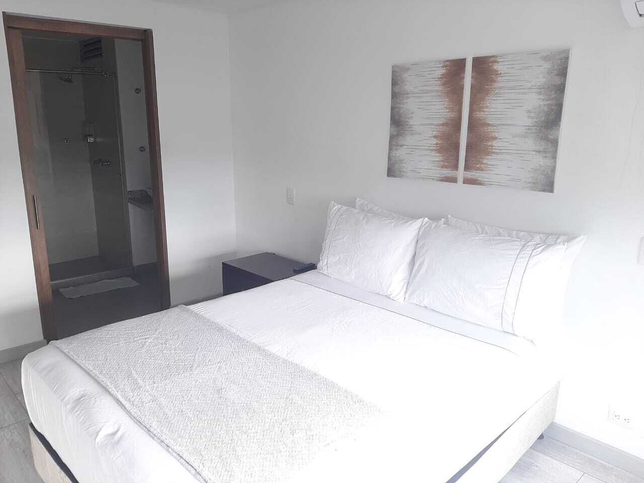 A bedroom with a bed, a nightstand, a wardrobe, and a wall-mounted artwork.