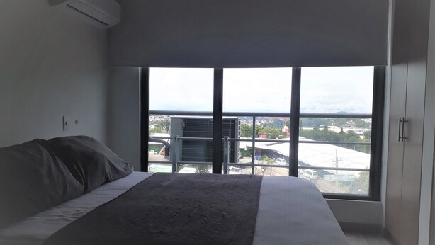 A bedroom with a large window, a bed, and an air conditioning unit. - apartamento amoblado una habitacion (pereira)