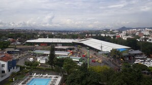 A view of a cityscape with a large parking area, a swimming pool, and a building with a green roof. - apartamento amoblado una habitacion (pereira)