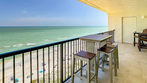 A balcony with a view of the beach and ocean.
