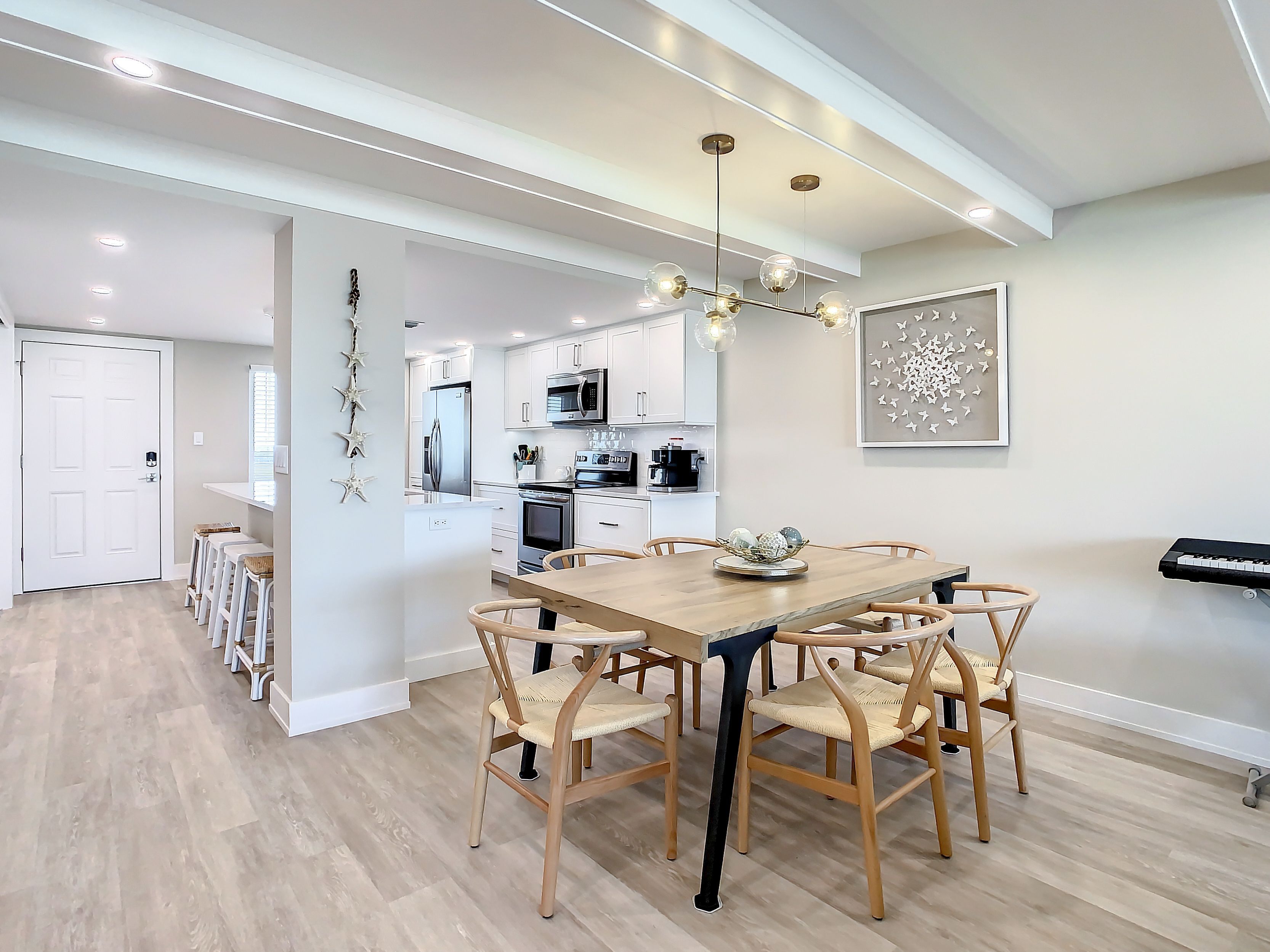 A modern kitchen with white cabinets, stainless steel appliances, and a dining area with a wooden table and wicker chairs.